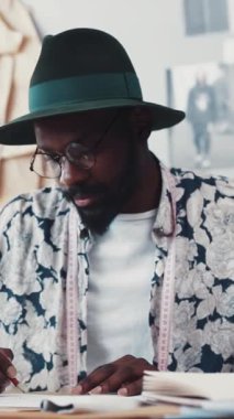 Bir moda tasarımcısı, canlı ve ilham verici bir çalışma alanında yaratıcılığını sergileyen çizimlere dikkatle odaklanır.