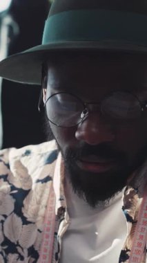 Düşünceli ve yaratıcı bir adam, şık bir çiçek gömleği ve uyumlu bir şapka giymiş, eşsiz tarzını sergiliyor.