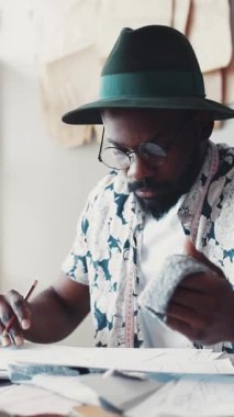 Odaklanmış bir adam kalemle özenle yazıyor, yaratıcılığını ve çalışma alanındaki eşsiz stilini gösteriyor.