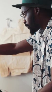 Parlak çiçekli bir gömlek giymiş bir adam ve zarif yeşil bir şapkası var. Yaratıcı bir sürece dalmış.