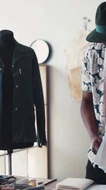 Şık ve şık bir tasarımcı yaratıcı çalışma alanındaki çizim ve kalıplarını titizlikle analiz eder.