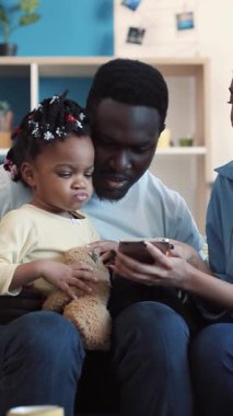 Yürek ısıtan bir sahne, neşeli bir ailenin akıllı bir telefonla etkileşimini, gülümsemesini ve mutluluğunu paylaşmasını gözler önüne seriyor.