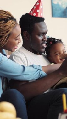 Sevgi dolu bir ebeveynin ve çocuklarının neşeli bir kutlamada oyuncak bir ayıyla eğlendiği yürek ısıtan bir an.