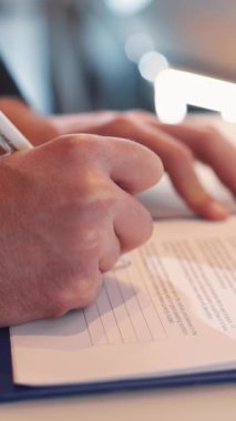 Profesyonel bir çalışma ortamında önemli bir belgeyi imzalamaya hazırlanan, elinde kalem tutan bir elin yakın plan resmi.