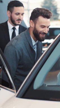 Bir adam zarif ve şık bir otomobil galerisinde sergilenen arabayı merakla inceliyor.