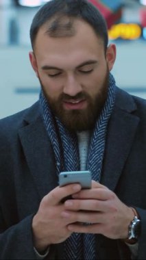 Bir erkek kış mevsimi için şık giyinirken akıllı telefonunu kullanma tecrübesinden zevk alır.