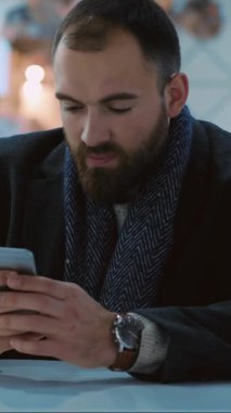 Modern ofis ortamında akıllı telefonunu kullanan odaklanmış bir adam, teknoloji ve bağlantıyı gösteriyor..