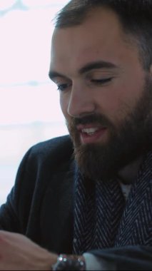 Odaklanmış bir adam akıllı telefonuyla meşgul olurken şık ve modern bir ortamda şık giyiniyor.