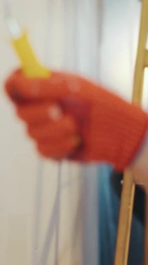 NEW YORK - 5 Nisan 2017: Eldivenleri koruyan bir el boya silindiri kullanır. Sıradan bir üniforma içindeki çekici genç müteahhit arka plandaki rendelendirme malasını kullanıyor. İşlem ya da onarım, yeni tasarım, profesyonel askerler. Yavaş çekim