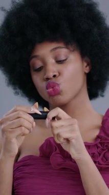 Kendine güvenen bir kadın zarif afro saç stilini sergiliyor. Güzelliğini arttırmak için parlak ruj sürüyor.