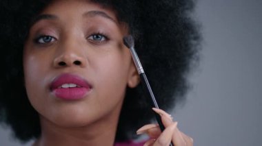 Fırça ve canlı renklerle makyaj yapan, modern güzellik eğilimlerini sergileyen birinin yakın çekimi.