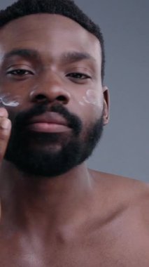 Özenli bir şekilde yüz kremi süren bir adamın yakın çekim görüntüsü, özgüven ve sükunet temalarını vurguluyor.