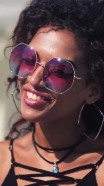 Genç ve güzel bir kadın. Güneş gözlüklü bir adamla konuşuyor. Gülümsüyor, gülümsüyor, rahatlıyor.