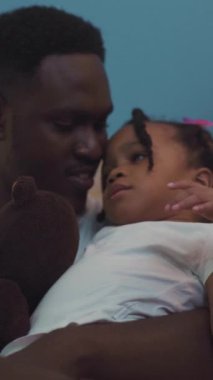 Bir erkeğin küçük bir kızı kucaklayıp derin bağlarını sergilediği hassas bir an başlıyor. Sıcaklıkları aile ilişkilerinin güzelliğini vurguluyor.