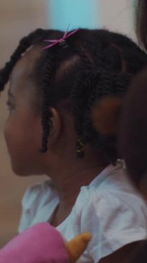 Saçı örgülü ve çiçekli, içi doldurulmuş bir hayvanı nazikçe tutan çocukluk sevinci ve masumiyetini somutlaştıran küçük bir kızın iç açıcı bir sahnesi.