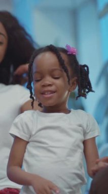 Sevgi dolu yetişkinler tarafından tutulan beyaz tişörtlü küçük bir kızın aile bağlarının sıcaklığını gösteren ve neşe saçan iç açıcı bir video.