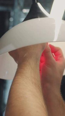 Genç adam modern ofisin beyaz tavanına ampul yerleştiriyor. Ampul farklı renklerde parlıyordu. Kapalı.