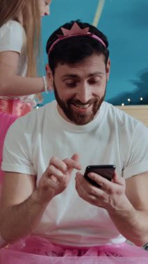 Bir baba ve kızı dans ederken neşeli bir anı paylaşıyor. Pembe etekli kız, ona katılırken hareketlerini sergiliyor, eğlenceyi yakalıyor.