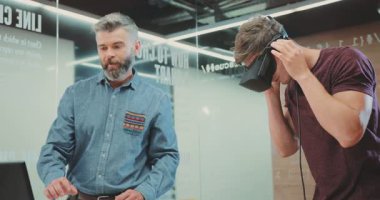 Bu ilgi çekici video modern bir odada iki adamı gösteriyor, biri VR kulaklıklı. Konuşmaları sanal gerçekliğin heyecan ve sosyal yönlerini gözler önüne seriyor.