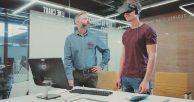 Modern bir ofiste, sanal ortama dalmış, yenilikçi projeleri araştıran ve işbirliği yapan, teknoloji sinerjisi sergileyen iki adam VR kulaklıkları kullanır.