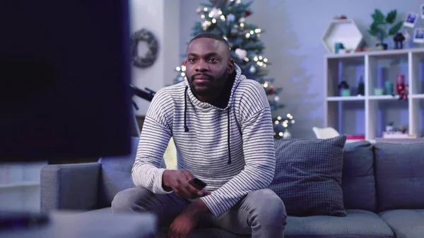 Sakallı, güzel oturma odasındaki koltukta oturan ve televizyon kanallarını değiştiren konsantre bir adam. Adam ayakta duruyor ve televizyonu kapatıyor..