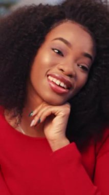 Kıvırcık saçlı, televizyon izleyen genç bir esmer. Harika bir Noel ağacının arka planında gülümseyen Afrikalı kız. Kapalı.