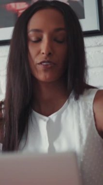 Genç, güzel bir mulatta kadın bilgisayarın başında oturmuş görüntülü konuşma yapıyor. Evde, mutfakta. Mutlu hissettiriyor. Modern tasarım. RED Epic Camera 'da Çekim.