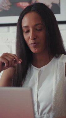 Genç, güzel bir mulatta kadın bilgisayarın başında oturmuş görüntülü konuşma yapıyor. Evde, mutfakta. Mutlu hissettiriyor. Çubuklar. Modern tasarım. RED Epic Camera 'da Çekim.