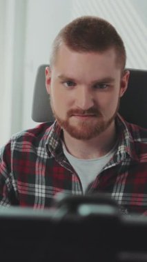 Genç sakallı bir adam bilgisayarın başında oturuyor. Ofiste çalışıyor. Çağdaş tasarım. RED Epic Camera 'da Çekim.