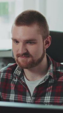 Genç sakallı bir adam bilgisayarın başında oturuyor. Ofiste çalışıyor. Mutlu hissettiriyor. Çağdaş tasarım. RED Epic Camera 'da Çekim.