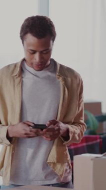 Afrikalı genç evli çift yeni bir daireye taşınıyor. Tablet bilgisayar kullanan neşeli bir adam dikkatlice hazırlanan kutuları sayıyor..