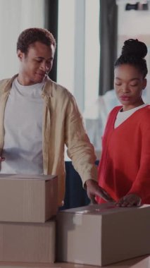 Mutlu, heyecanlı, evli, Afro-Amerikalı bir adam ve kadın boş eski bir dairedeki mobilyaları olan karton kutuları sayıyorlar. Taşınan ev.