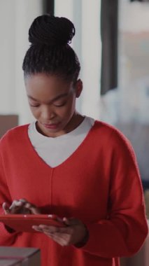 Tablet bilgisayar uygulaması kullanan, kutuları hazırlayan ve kameraya mutlu poz veren Afrikalı genç bir kadının portresi. Ailemden ayrılıyorum..