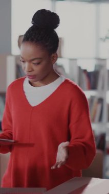 Siyah, genç, çekici bir kadın, kutuları sayıp her şeyi kontrol ediyor. Taşınmak için dijital tabletleri kullanıyor..