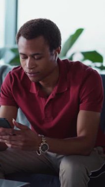 Akıllı telefonlu ve kulaklıklı genç, Afro-Amerikan iş adamı. Öğleden sonra evde eğlencesine müzik dinliyor..