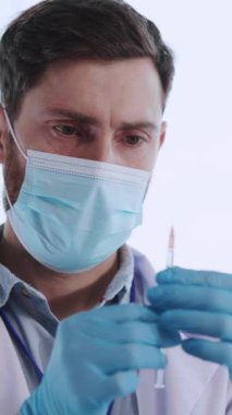 Kafkasyalı genç bir eczacı, laboratuarda yaşlı kadın hastaya aşı sıvısı enjekte ediyor. Coronavirus gribi. Salgın.