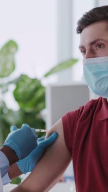 Afrika kökenli Amerikalı doktor, erkek hastahanesinde grip gribine karşı aşı yapıyor..