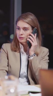 Odaklanmış bir iş kadını, bir iş görüşmesi sırasında aktif olarak işle ilgili bir telefon görüşmesi yapmaktadır.