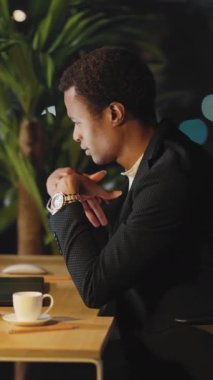 Düşünceli ve düşünceli bir iş adamı, elinde sıcak bir fincan kahve tutarken derin derin düşünen, antika bir kafe masasında oturur.