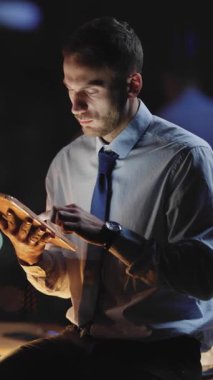 Kendini işine adamış bir işadamı şık ve çağdaş bir ofis ortamında zarif bir tabletle meşgul.