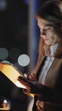 Bir iş kadını tabletine derinden dalmış vaziyettedir. Bu da modern ofis ortamında yüzünü zarifçe aydınlatır.