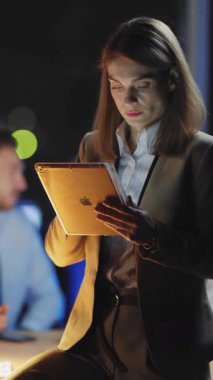 Uzman bir kadın, loş bir ofiste yoğun bir şekilde belgeleri inceliyor. Konsantrasyon ve adanmışlık gösteriyor..