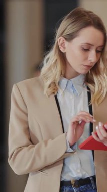 Kafkasyalı sarışın ofis yöneticisi iş merkezinde iş arkadaşı olarak dolaşan tablet bilgisayar kullanan bir kadın. Şirket konsepti. İş kadını..