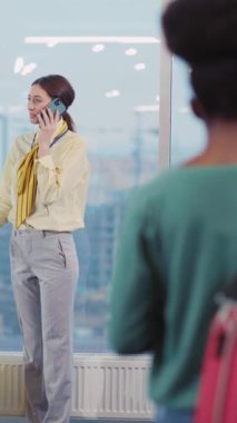 Bu videoda, sarı bavulu olan bir kadın güneşli bir pencerenin yanında telefonuyla birden fazla iş yaparken, başörtüsü takan bir kadın seyahate hazır olmayı simgeliyor.