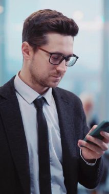 Takım elbiseli bir adam cep telefonuyla acil bir iş görüşmesine odaklanmış, profesyonelliği ve iletişimi bir şirket ortamında yansıtıyor.