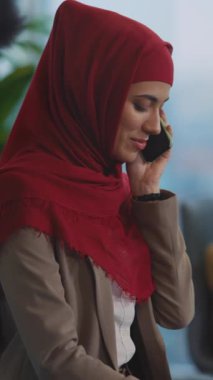 Parlak kırmızı tesettürlü bir kadın telefonuyla konuşuyor. Kişiliğini ve sohbetinin önemini anlatıyor.