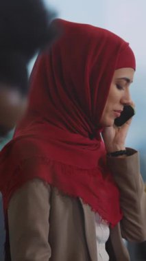 Videoda kırmızı tesettürlü bir kadın cep telefonuyla konuşuyor, anlamlı jestlerini ve sıcaklığını gündelik bir ortamda vurguluyor.