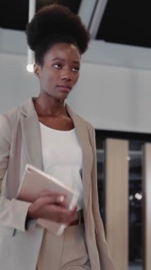 Kendine güvenen Afro-Amerikan zarif kadın yönetici şirket koridorunda ilerlerken ofis kabinesine giriyor. İş adamı.