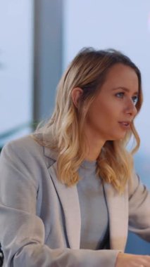 İş yerinde oturan sarışın çekici bir kadın iş merkezindeki iş arkadaşlarıyla iletişim kuran kız kardeşiyle konuşuyor..