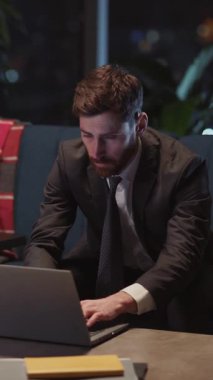 Haberleri kontrol etmek için ofis bilgisayarından eve dönen sakallı, genç, yetişkin bir iş adamı. Yorgunluk, bunalmış insan.